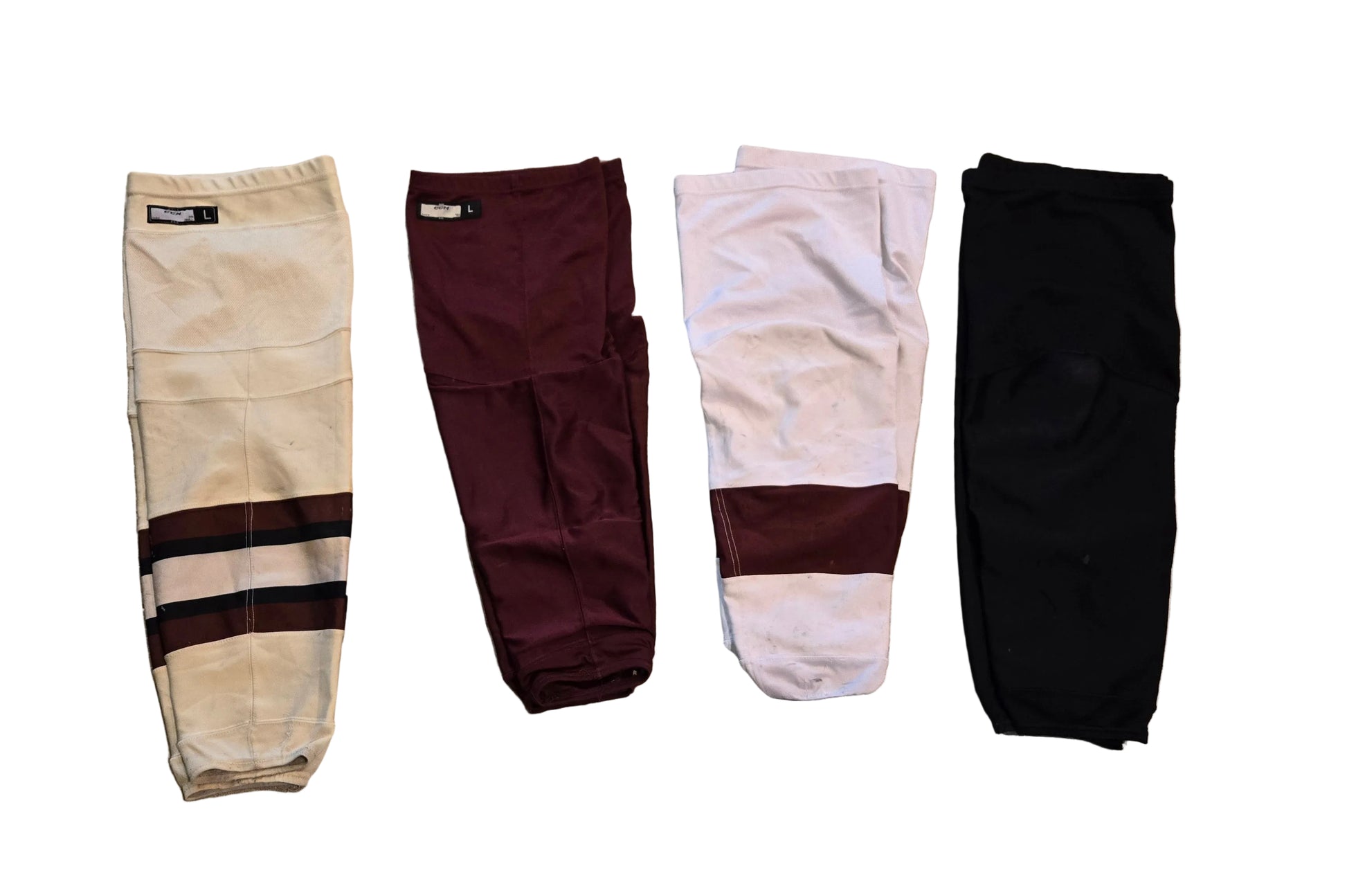 Four pairs of hockey socks, shown in cream, maroon, white and solid black.